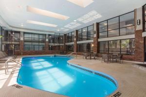 a large pool in a building with tables and chairs at The Clover Hotel, Ascend Hotel Collection in South Bend