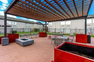 a patio with tables and chairs and a wooden pergola at The Clover Hotel, Ascend Hotel Collection in South Bend