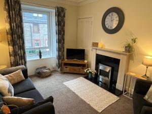 a living room with a fireplace and a clock on the wall at Cherrybank apartment in Perth