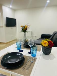 a table with two black plates and glasses and flowers at Petite Maison Proche aéroport Charles de Gaulles in Drancy
