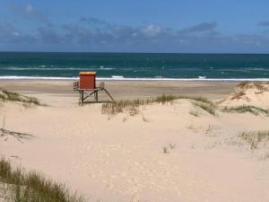 um banco sentado numa praia junto ao oceano em Casa grande 3 dormitorios playa alvorada em Barra del Chuy
