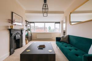 ein Wohnzimmer mit einem grünen Sofa und einem Tisch in der Unterkunft Bright & Delightful 2BD Flat Clifton Down Bristol in Bristol