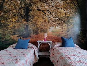 a bedroom with two beds and a tree mural at Giaveno, apartment "margherita" a pochi passi dal centro, wifi in Giaveno