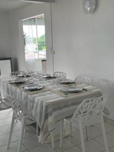 een eettafel met een wit tafelkleed en stoelen bij Le Tamarinier in Sainte-Anne