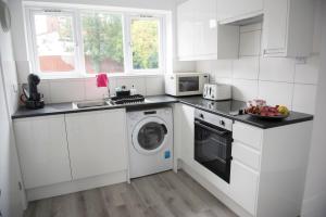 a white kitchen with a washing machine and a microwave at Mowbray Quarters of Cambridge in Cambridge