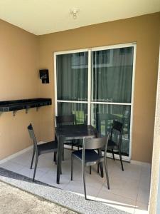 d'une salle à manger avec une table, des chaises et une fenêtre. dans l'établissement Apê do Tigas - Praia dos Milionários, à Ilhéus