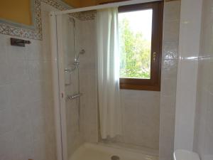 uma casa de banho com um chuveiro, uma janela e um lavatório. em Apartamentos La Cruz de Paderne em Navia