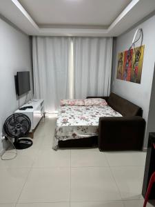 a bedroom with a bed and a desk and a television at Apê do Tigas - Praia dos Milionários in Ilhéus