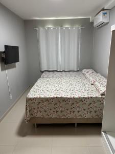 Dormitorio pequeño con cama con cortina en Apê do Tigas - Praia dos Milionários, en Ilhéus