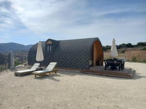 a small house with two chairs and umbrellas at Glamping Pod in Prodhromi