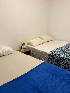 a room with two beds and a table with a lamp at Apartamento 2 quartos Copacabana in Rio de Janeiro