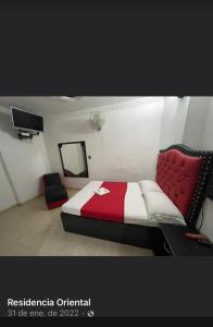 a bedroom with a red and white bed and a television at Residencias del Oriente in Bucaramanga