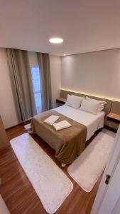 a bedroom with a large bed with two towels on it at Elegante Apartamento, com ótima localização, na principal avenida de entrada em Bagé in Bagé
