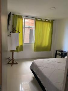 a bedroom with a bed and a window with yellow curtains at Tunja Magic Habitación. in Tunja