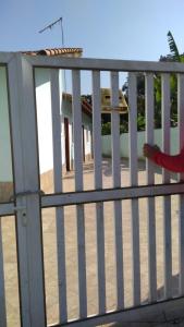 una persona in piedi su un portico con una recinzione bianca di casa na praia Itanhaém a Guarulhos