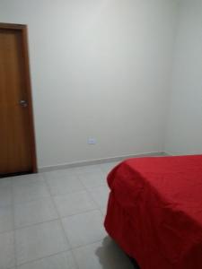 a bedroom with a red bed and a white tile floor at casa na praia Itanhaém in Guarulhos