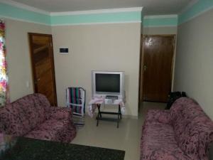 uma sala de estar com dois sofás e uma televisão em casa na praia Itanhaém em Guarulhos