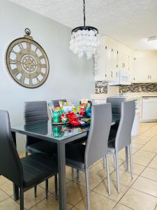 a dining room table with chairs and a clock on the wall at The Chelsea House Villas, Gorgeous condo-OceanView-Jacuzzi in Myrtle Beach