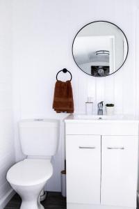 La salle de bains blanche est pourvue de toilettes et d'un miroir. dans l'établissement Rustic Rails Accommodation, à Dargaville