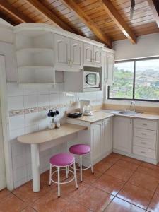 a kitchen with white cabinets and two purple stools at Hermoso departamento en Quito con servicios incluidos in Quito