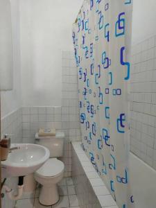 a bathroom with a toilet and a sink and a shower curtain at Hermoso departamento en Quito con servicios incluidos in Quito