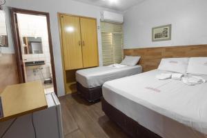 a hotel room with two beds and a bathroom at Hotel Terra Cedro In in Goiânia