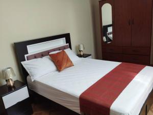 1 dormitorio con 1 cama blanca grande y 2 mesitas de noche en Apart Florencia, piscina en el verano! incluye parking y vigilancia 24 horas!, en Tacna