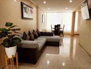 ein Wohnzimmer mit einem Sofa und einem Tisch in der Unterkunft Apart Florencia, piscina en el verano! incluye parking y vigilancia 24 horas! in Tacna