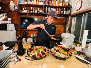 a man preparing food in a kitchen with two bowls of food at HOSTEL OE in Yoshinogawa