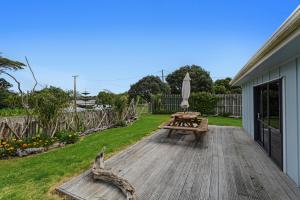 a wooden deck with a picnic table and an umbrella at Sandbach - Ohiwa Harbour in Waiotahi