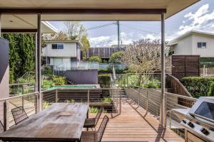 an outdoor deck with a wooden table and chairs at 11 East Gosford Luxury Waterfront House with Private Wharf in Gosford