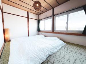 上富良野町にあるKamifurano Houseのベッドルーム1室(白いベッド1台、窓2つ付)
