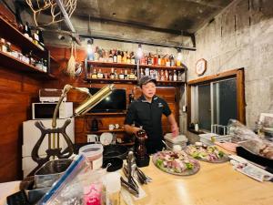 a man standing in a kitchen preparing food at HOSTEL OE in Yoshinogawa