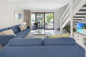 sala de estar con sofá azul y TV en Noosa Place Resort en Noosaville