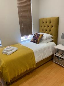 a bedroom with a bed with a yellow blanket at The Skinny Expat in Paarl