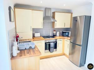 uma cozinha com balcões de madeira e um frigorífico de aço inoxidável em Modern 3 Bedroom House With FREE Parking em Kenton