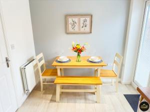 a dining room table with a vase of flowers on it at Modern 3 Bedroom House With FREE Parking in Kenton