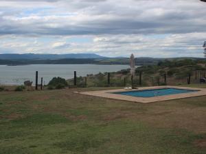 a swimming pool in a field next to a body of water at Verdant Valley Lodge in Albert Falls