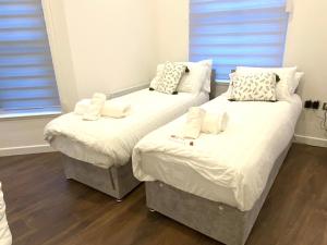 two twin beds in a room with wood floors at Buckinghamshire Elegant Studio in Buckinghamshire
