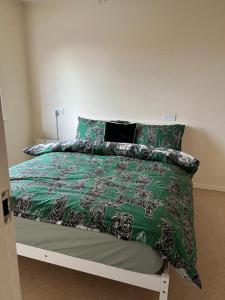 a bedroom with a bed with a green comforter and pillows at Maidstone, Birmingham, Uk in Birmingham