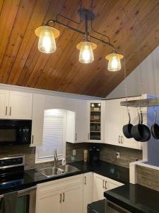 Il comprend une cuisine avec des placards blancs et un plafond en bois. dans l'établissement Charming Nordic Style - 2BR + 1 Bath Entire House, à Sudbury