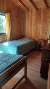 a bedroom with two beds in a wooden cabin at Hostel Calafquen Coñaripe in Coñaripe