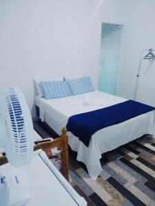 a bedroom with a white bed and a fan at Pousada Recanto da Preguiça in Jarinu