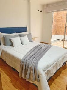 uma grande cama branca num quarto com uma janela em HERMOSO APTO CHICO em Bogotá