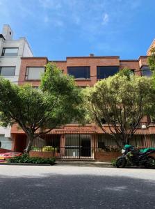 a building with trees and a motorcycle parked in front of it at HERMOSO APTO CHICO in Bogotá