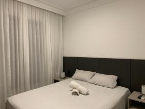 1 dormitorio con 1 cama grande con sábanas blancas en Apart hotel, 2 quartos - Caminho das árvores, en Salvador