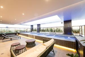 a swimming pool in a building with a couch and tables at Gaudium Apart-hotel por Quarto à Vista in João Pessoa