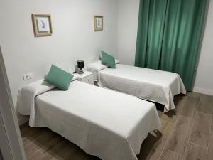twee bedden in een kamer met groene gordijnen bij Ponce suite in Córdoba