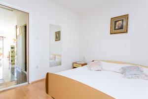 a white bedroom with a bed and a mirror at Apartment Seget Vranjica 1038b in Seget Vranjica