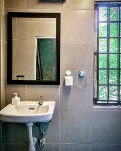 een badkamer met een wastafel en een spiegel bij LEJU 21 樂居 Explore Malacca from a riverside house in Melaka